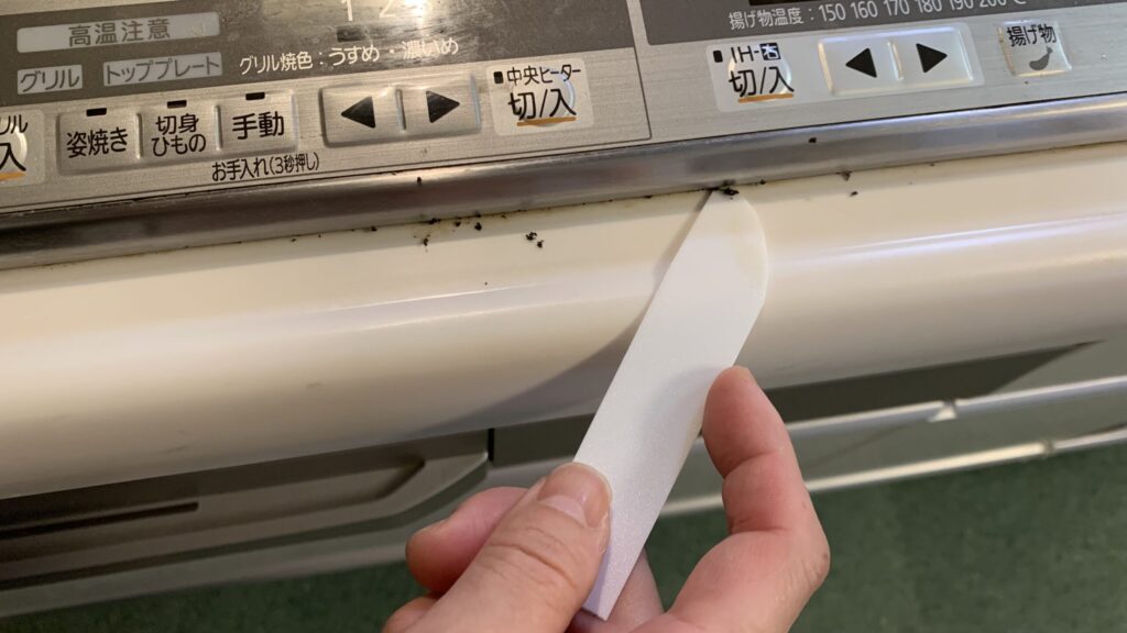 PPシートで作ったヘラで、コンロの隙間掃除をしている様子
