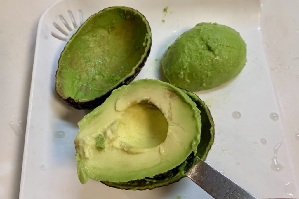 軽量スプーンでアボカドをくり抜いている写真