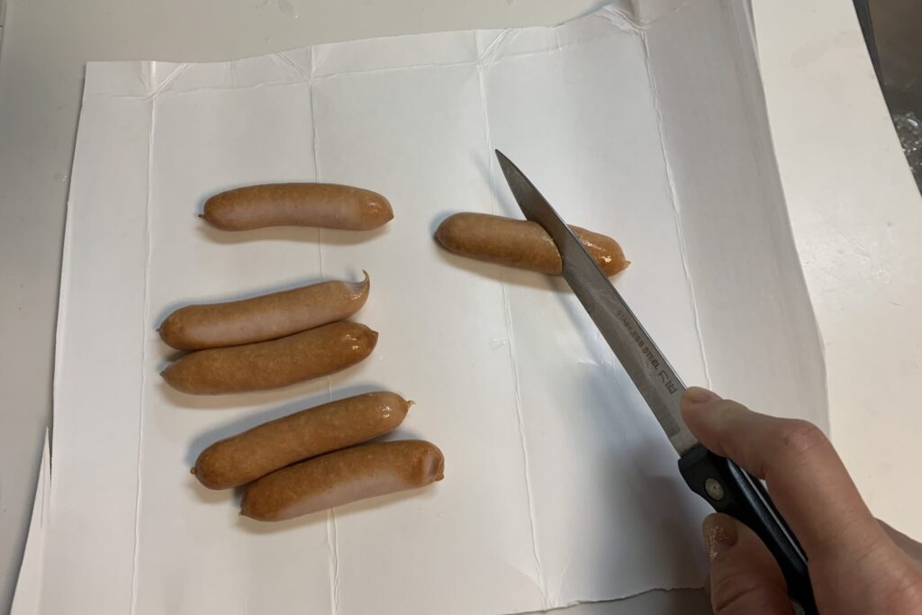 牛乳パックの上でカットするソーセージ